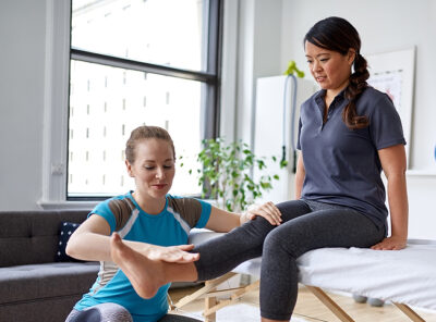 Female physiotherapist stretching leg and knee