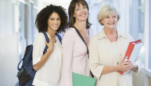 Three women standing in corridor with books